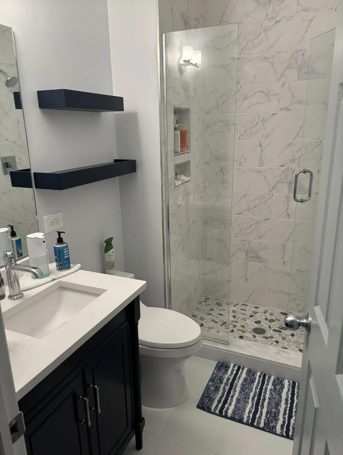 The same bathroom finished with new tile flooring, tiled shower, and painted walls