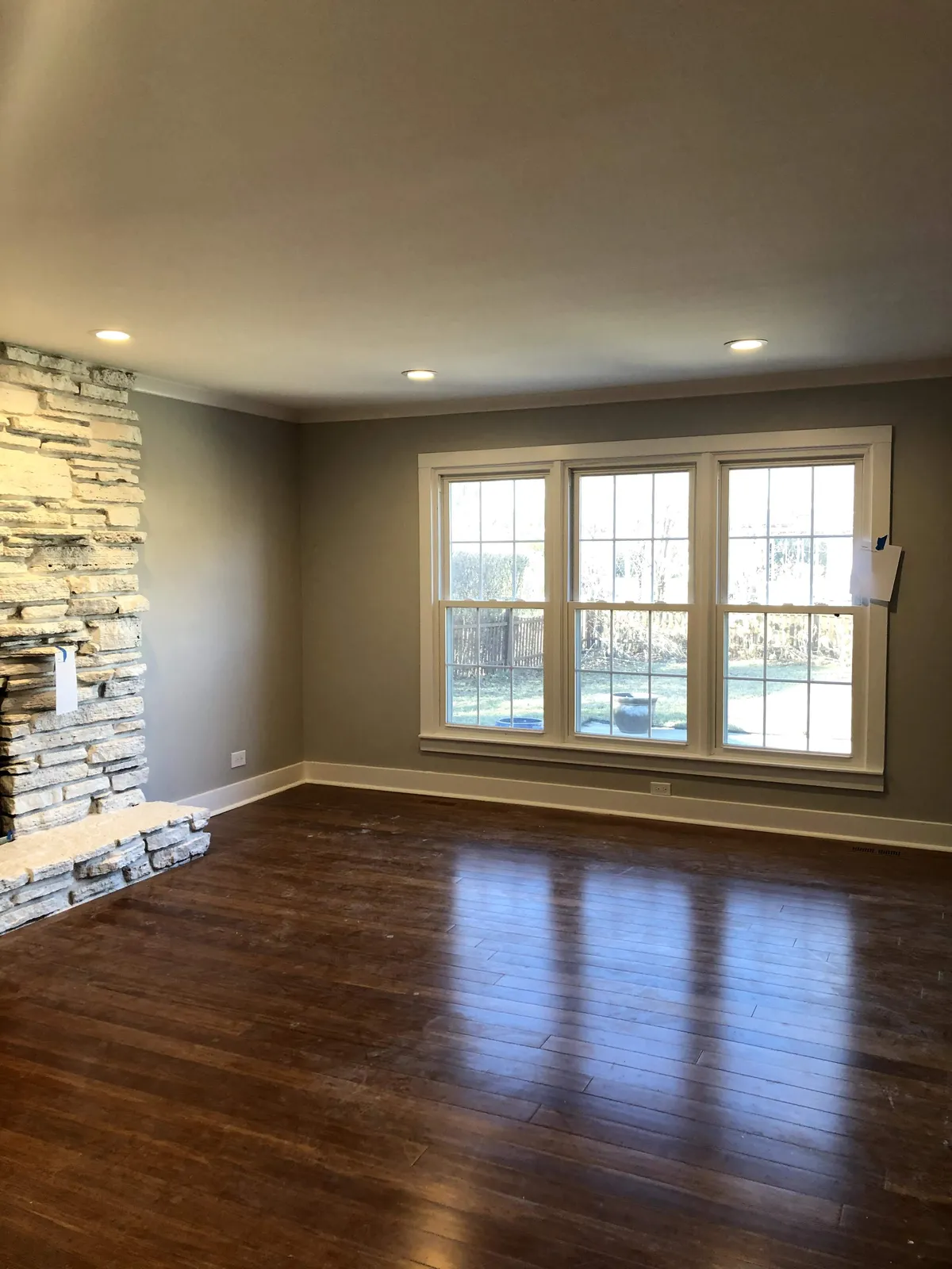 Living room with a stone fireplace surround and hardwood flooring after renovation