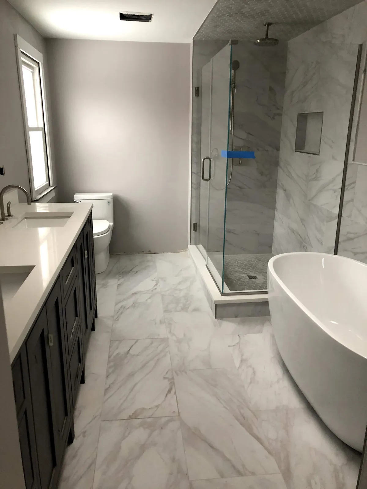 Finished marble-look tile bathroom with tiled shower surround installed by Green Wave Construction