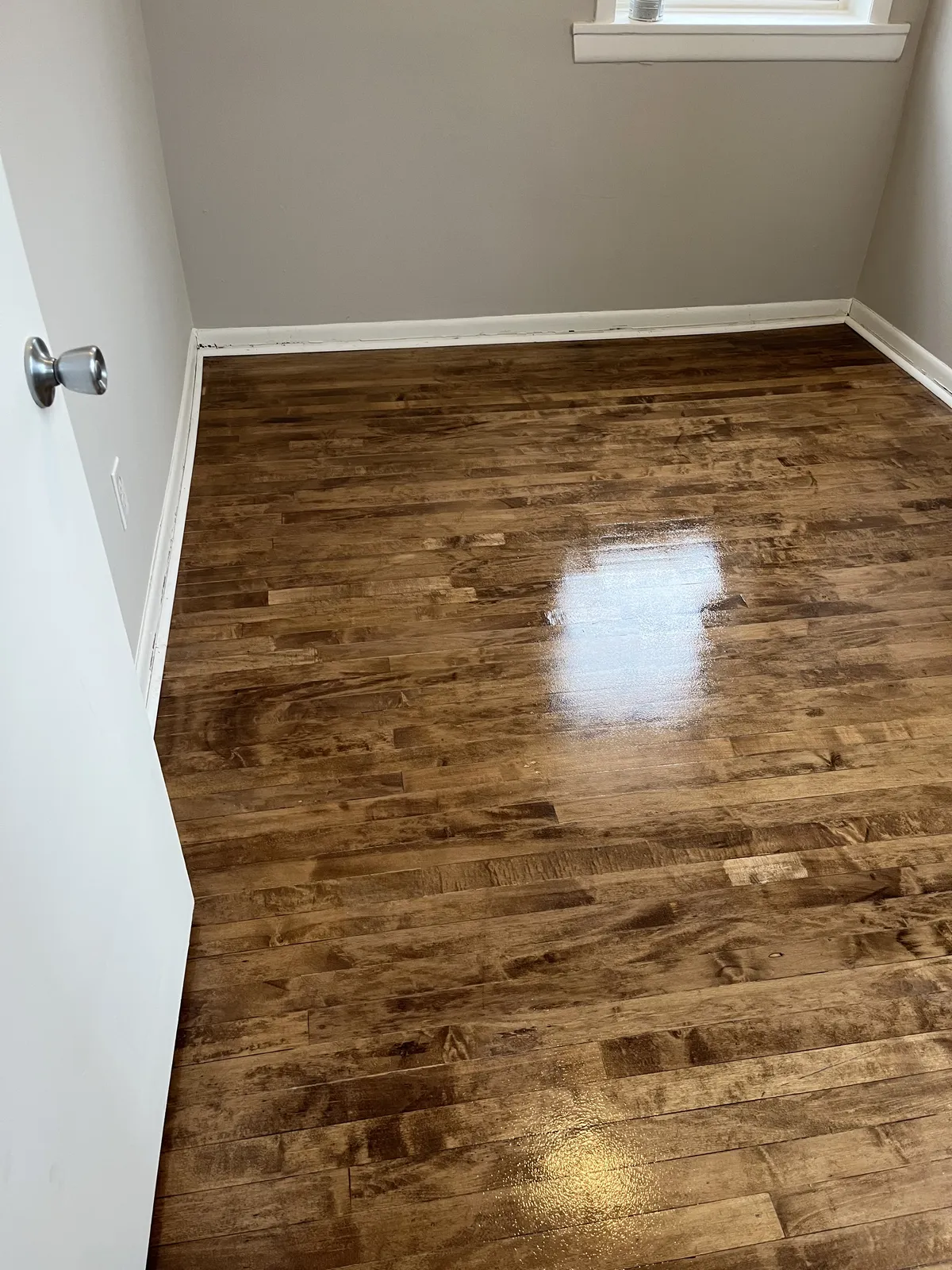 Refinished hardwood flooring running through a freshly painted Chicago bedroom completed by Green Wave Construction