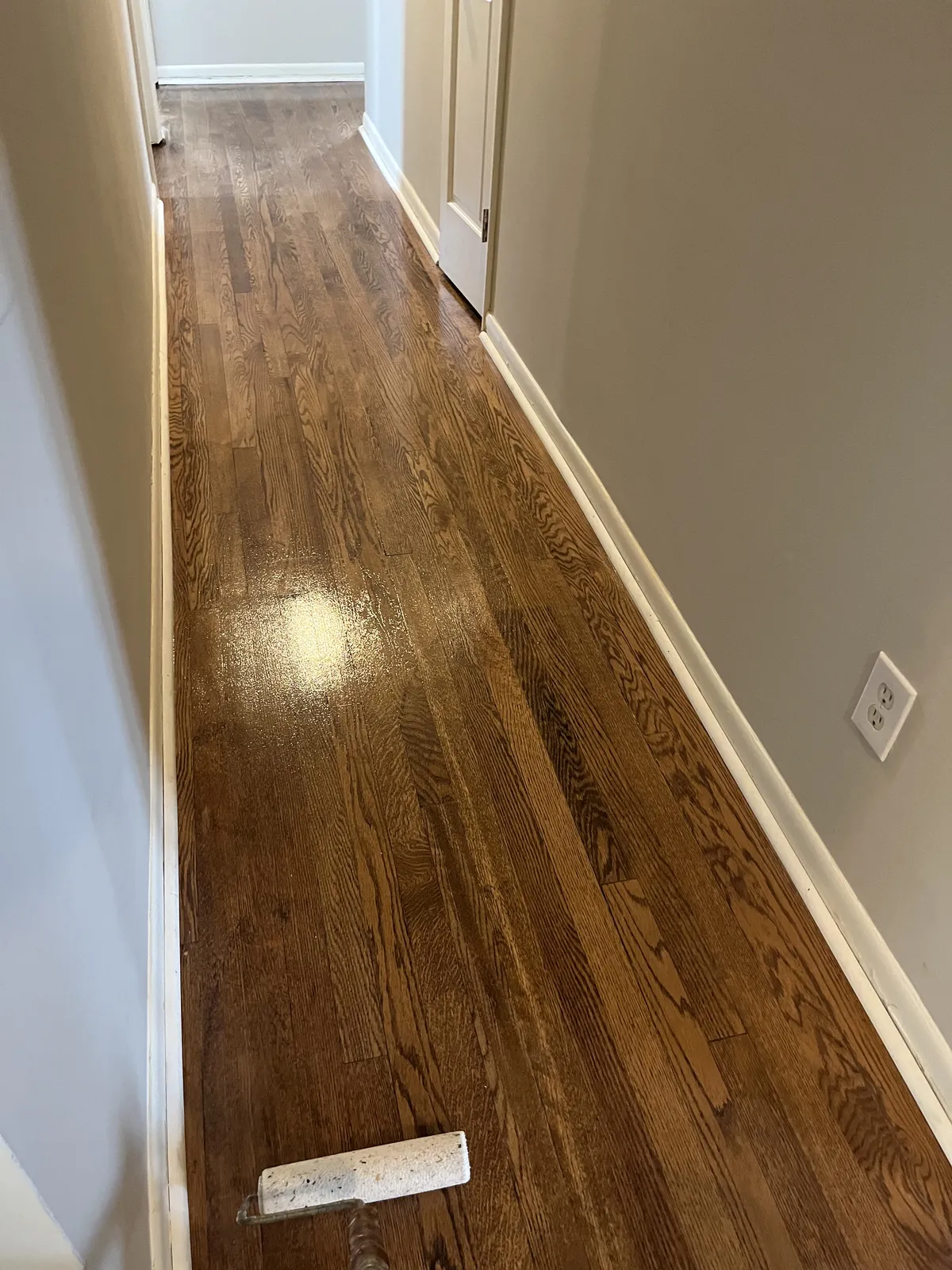 Hardwood flooring installed down a residential hallway with painted white trim and doors