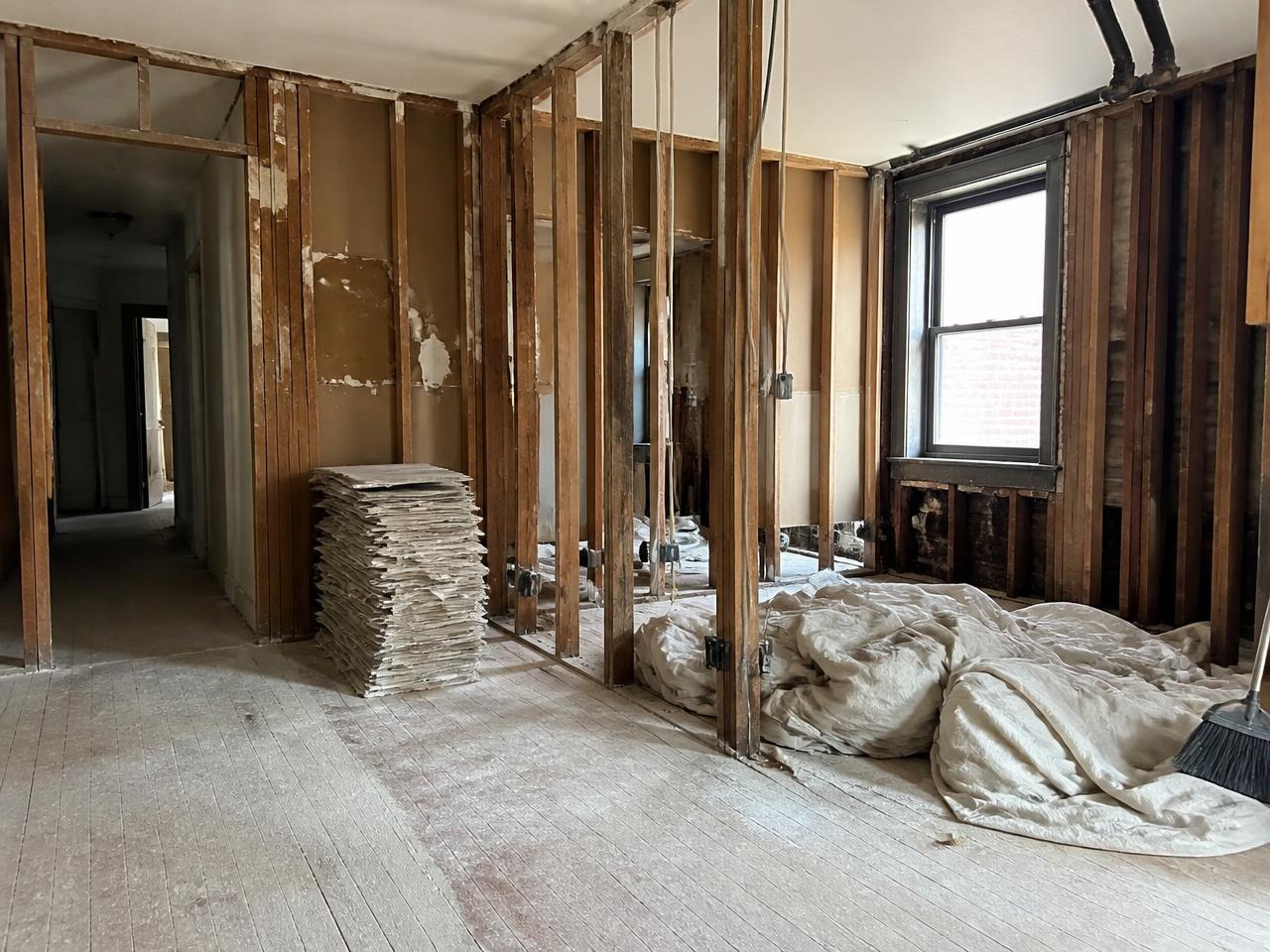 Interior demolition in progress with exposed studs and stacked drywall ready for hauling